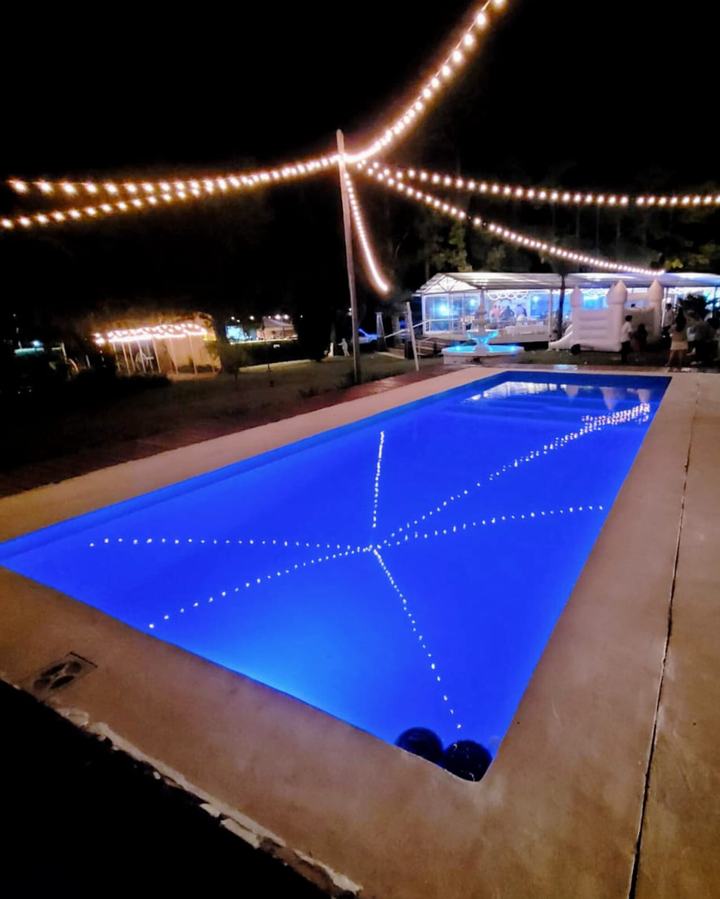 Piscina azul iluminada bajo guirnaldas