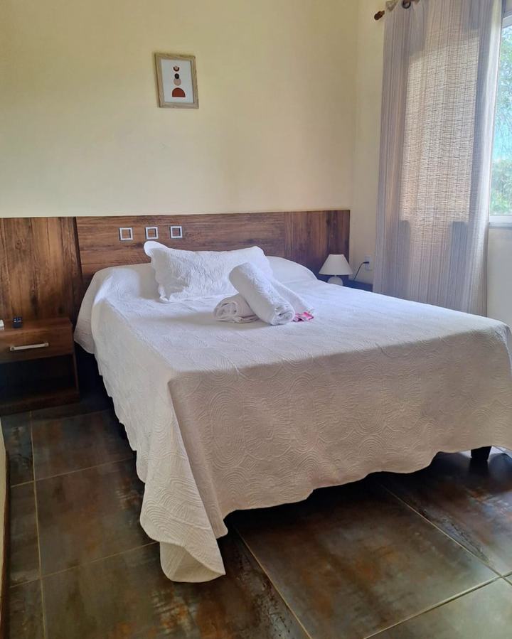 Cama matrimonial con respaldo de madera y toallas